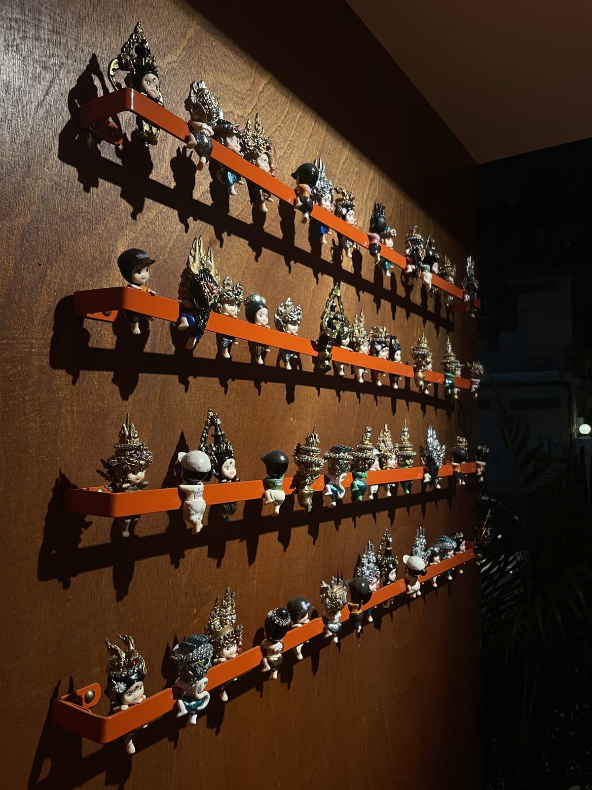 Rows of small carved figures displayed on shelves along a wooden wall