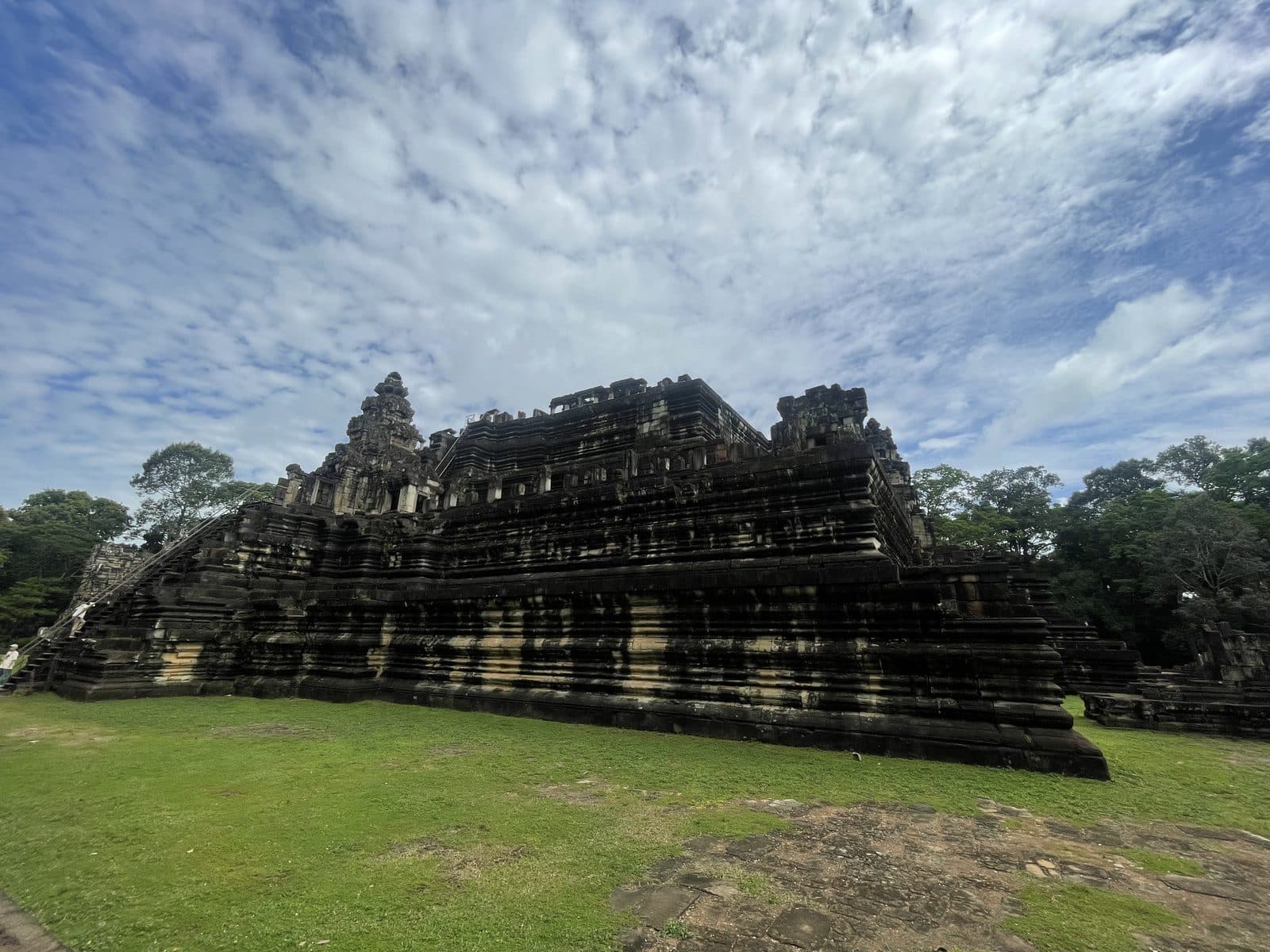 The stepped-pyramid form of Baphuon temple under a dramatic cloudy sky